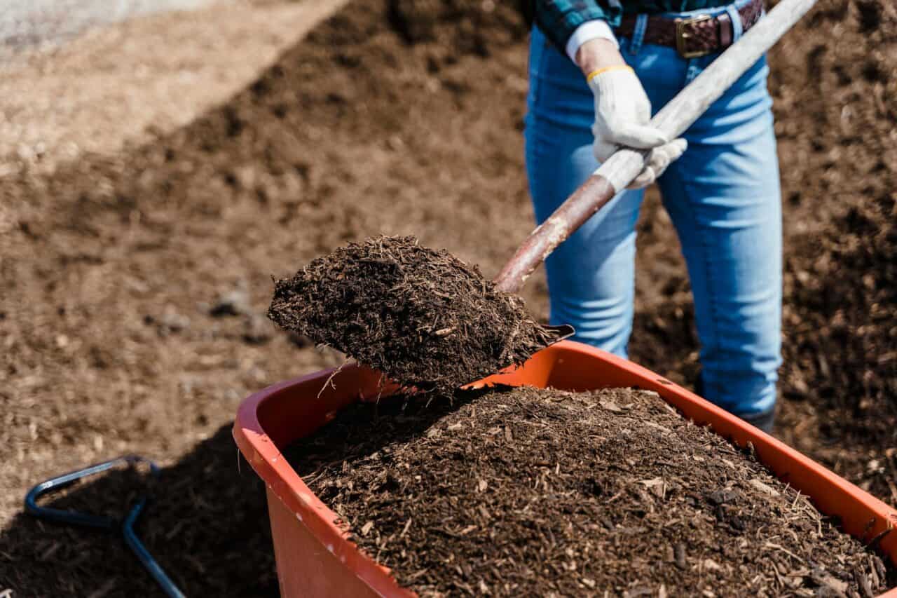 Záhradný kompostér s čerstvým kompostom a lopatou na jar