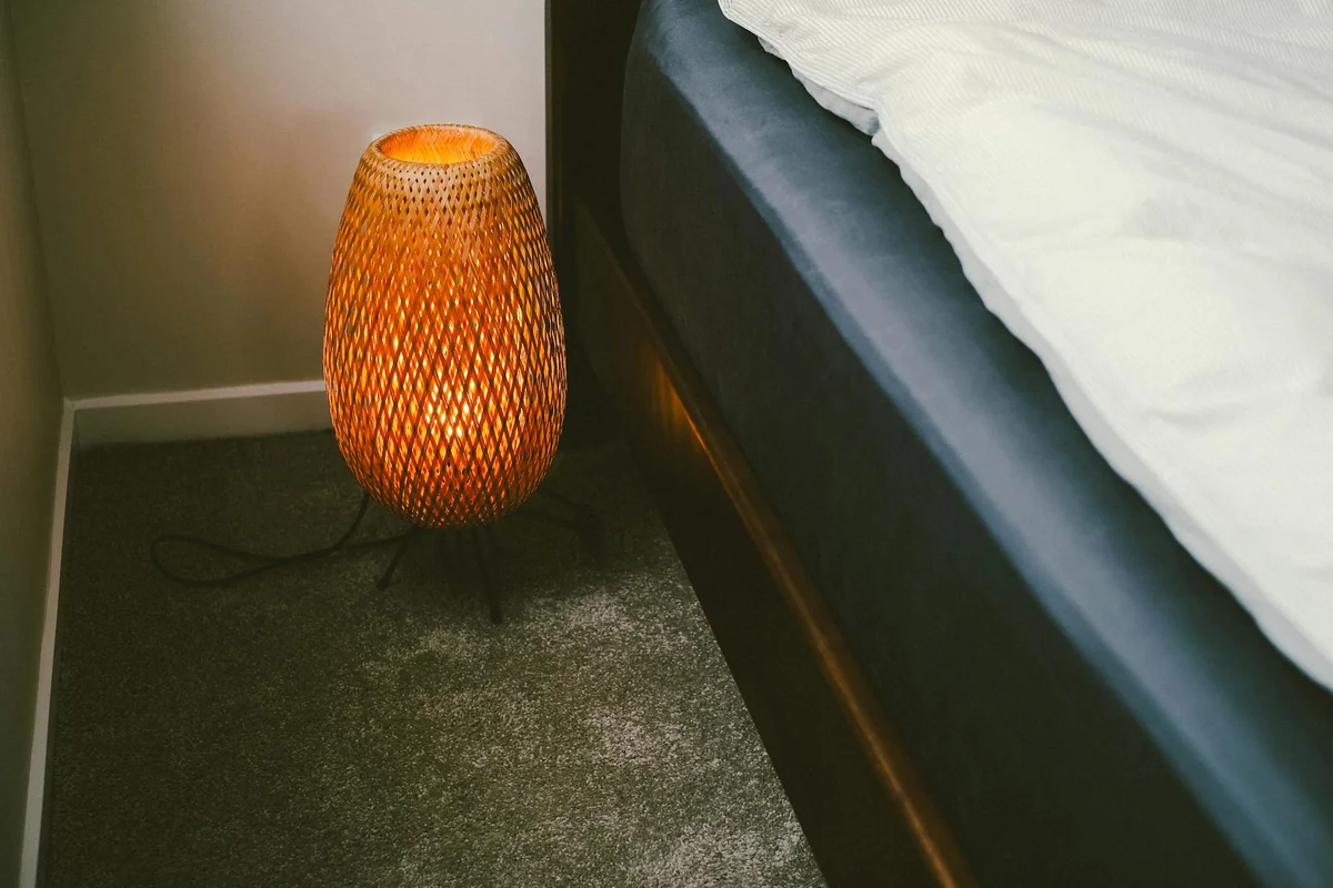 Warm wicker lamp adding cozy light to modern bedroom. Perfect for intimate and inviting home decor inspirations.