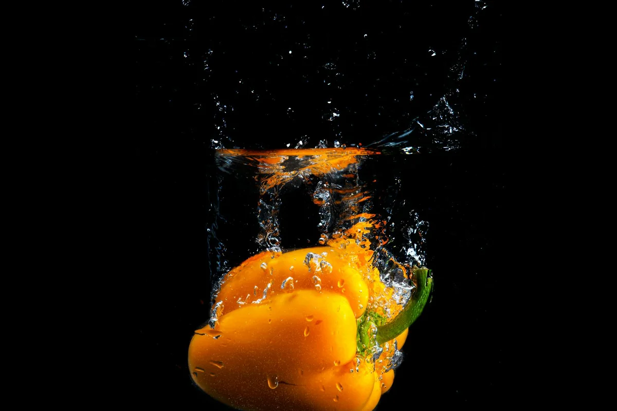 Yellow bell pepper splashes underwater, creating vibrant and fresh imagery.