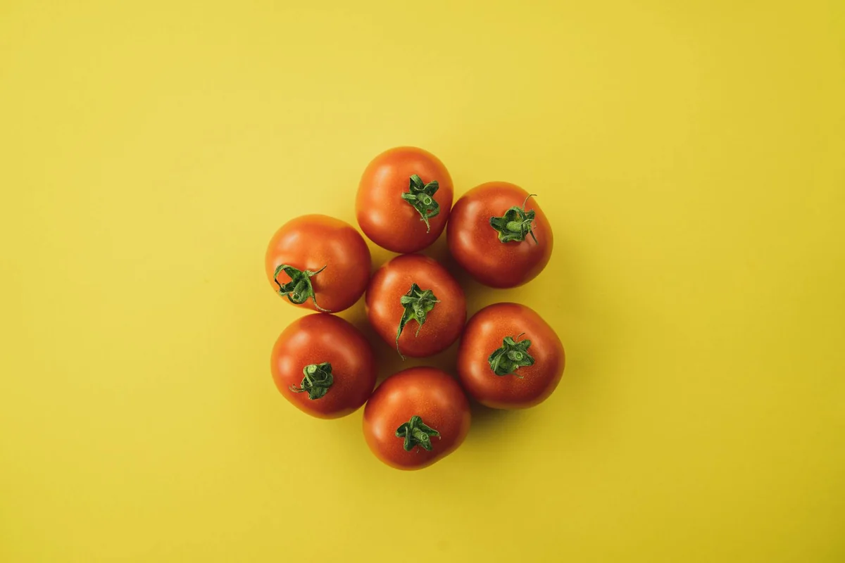 Top view of ripe tomatoes arranged on a vivid yellow surface, emphasizing freshness and nutrition.