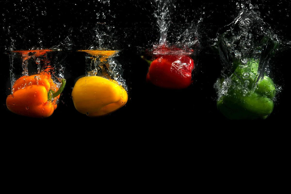 Vibrant bell peppers submerged in water showcase fresh produce in motion.