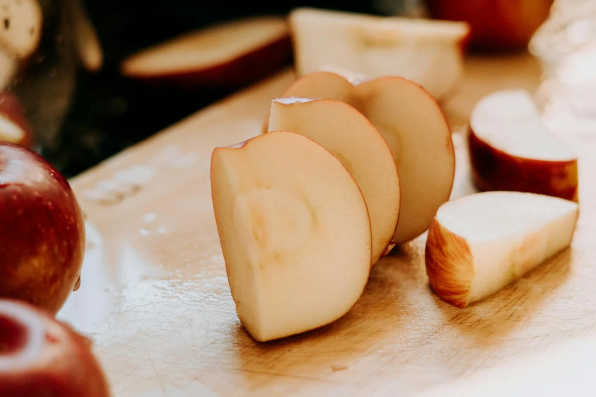 Close-up of fresh apple slices on a wooden cutting board, showcasing healthy snacking.