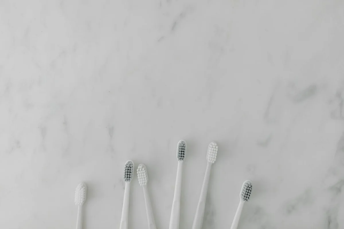 Five minimalist toothbrushes arranged on a marble surface, perfect for dental care themes.