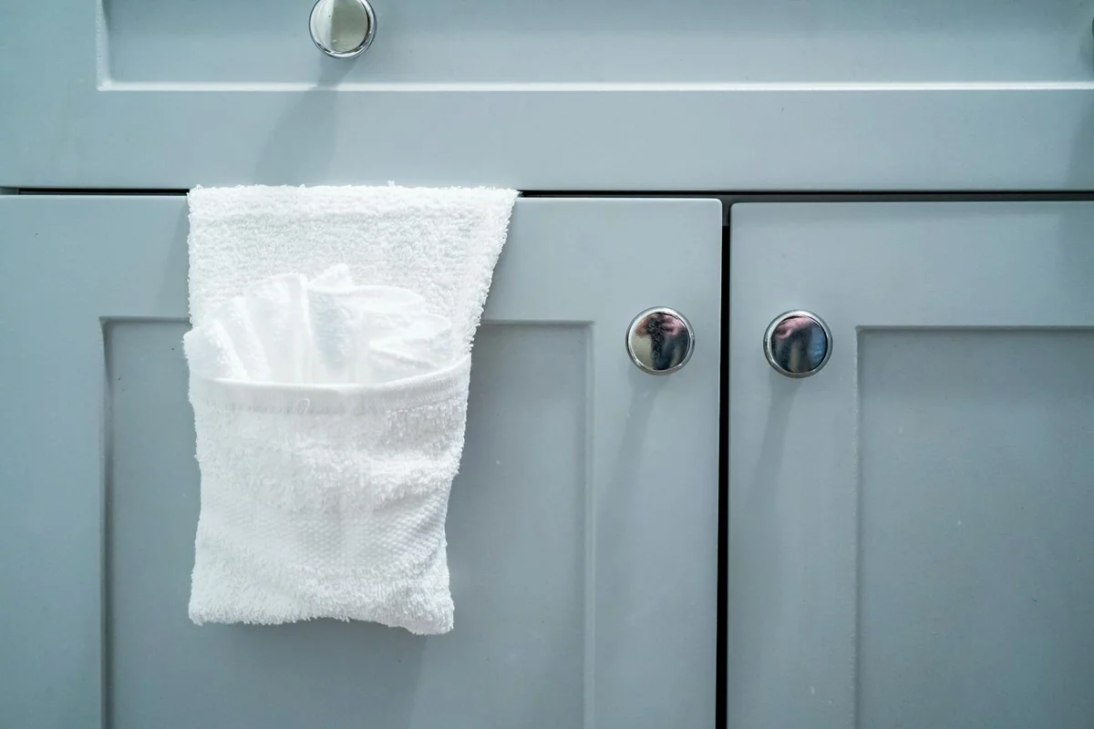 Close-up of a white towel on a modern gray bathroom cabinet door.