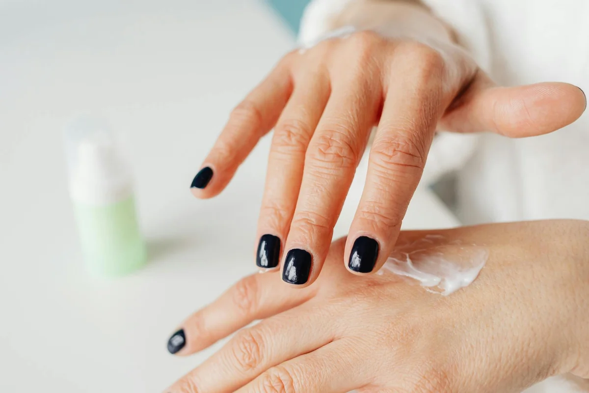 Close-up of a woman applying hand cream for moisturizing.